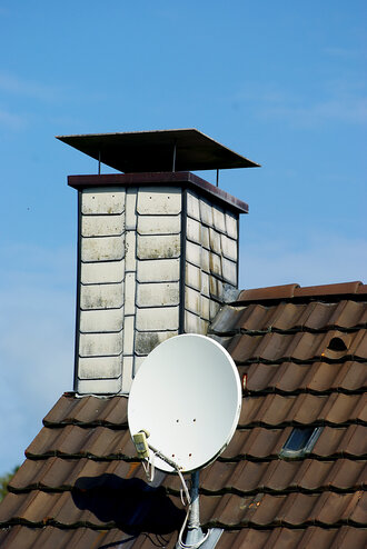 Bild: Hausdach mit Kamin und Satellitenschüssel