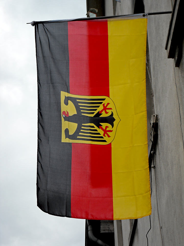 Bild: Nationalflagge mit Staatswappen: Bundesrepublik Deutschland (richtig von der anderen Seite und gedreht: von oben nach unten schwarz-rot-gold, Kopf des Adlers nach links)